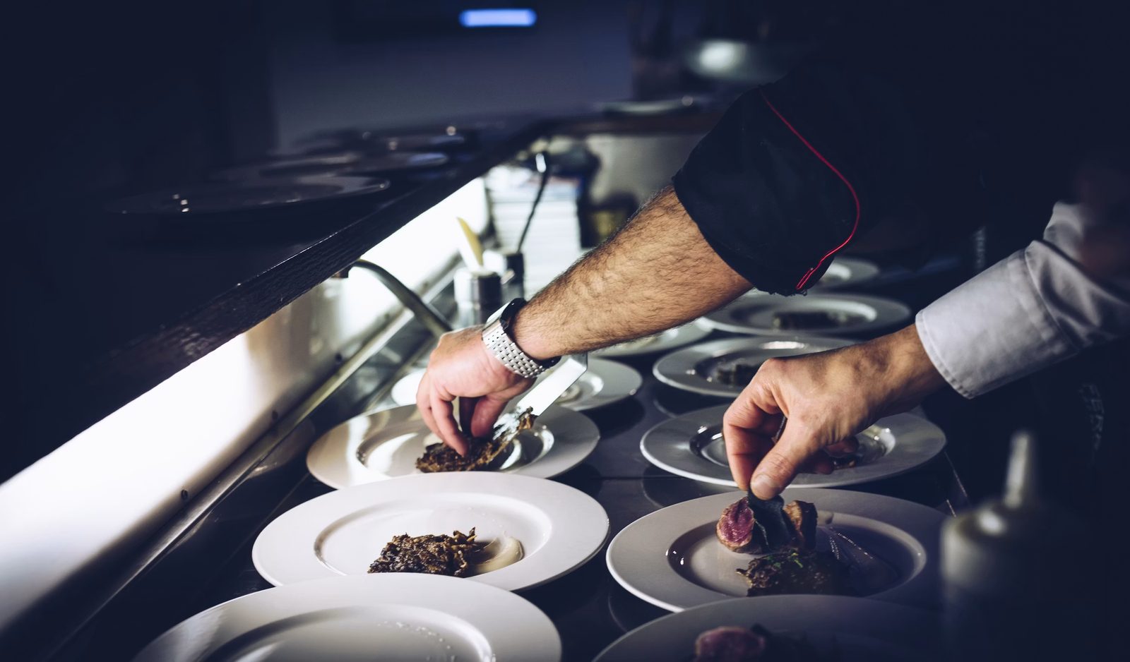 Chef plating dishes at the pass in the kitchen